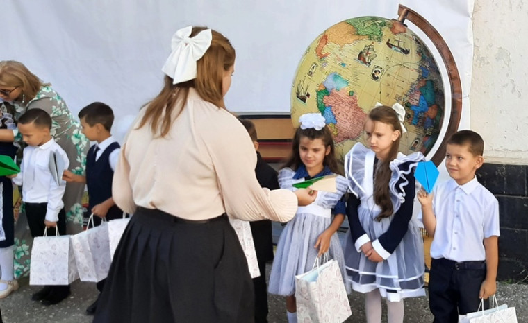 Первоклассникам вручают подарки.
